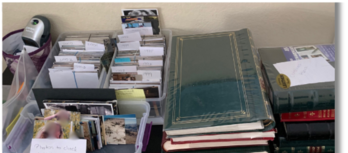 Printed photos sorted into labeled boxes beside family albums